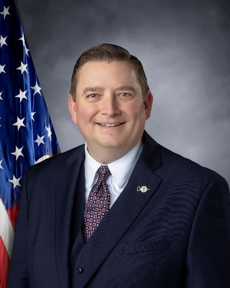 A photo of commissioner Chad Davis posed in front of the American Flag.