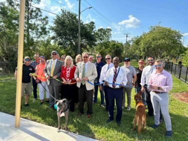A photo of the mayor, mayor pro-tem, commissioners, staff and partners unhooking two leashes. 