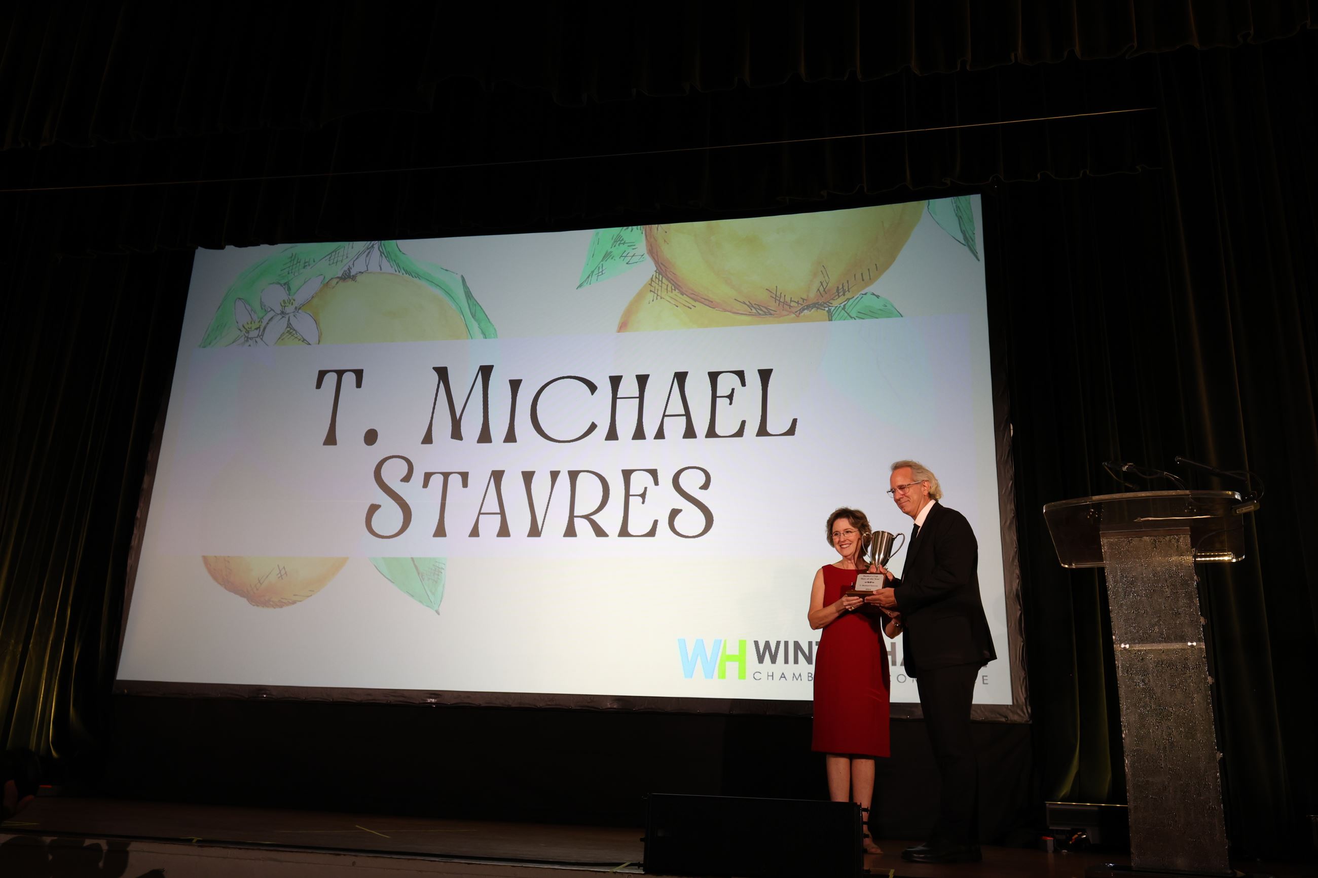 T. Michael Stavres on stage accepting the 2024 Banker's Cup Man of the Year award from Bonnie Par
